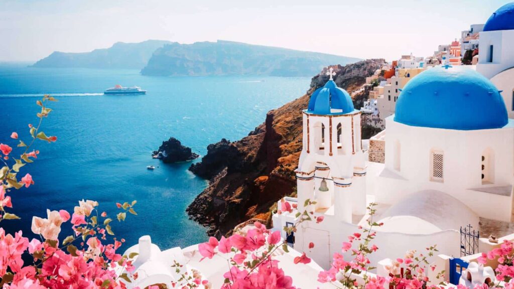 White-washed buildings with blue domes overlooking the Aegean Sea in Santorini, Greece.