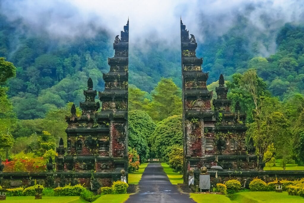 Lush green rice terraces, tropical palm trees, and a traditional Balinese temple in Bali, Indonesia